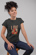 Woman wearing a black t-shirt with a graphic design of a cardinal and flowers, sitting on a stool against a plain background.
