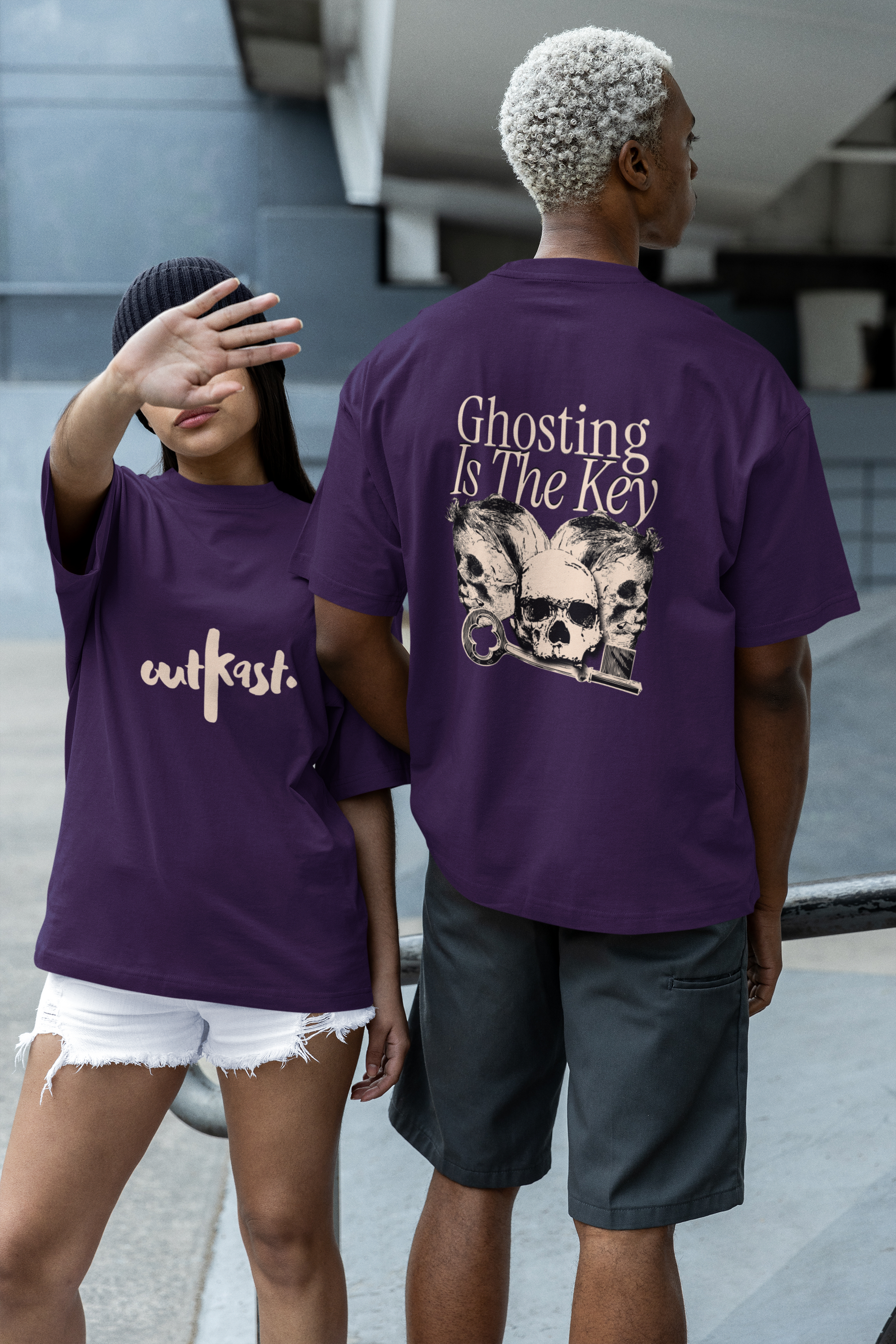 Two people wearing purple t-shirts with text and graphics, one facing the camera and the other showing the back.