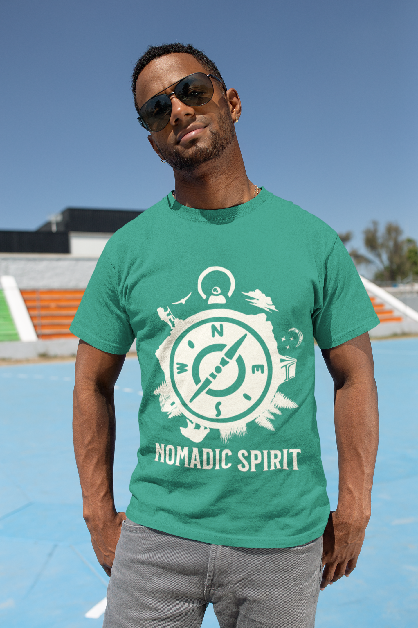Man wearing a green t-shirt with 'Nomadic Spirit' design outdoors.