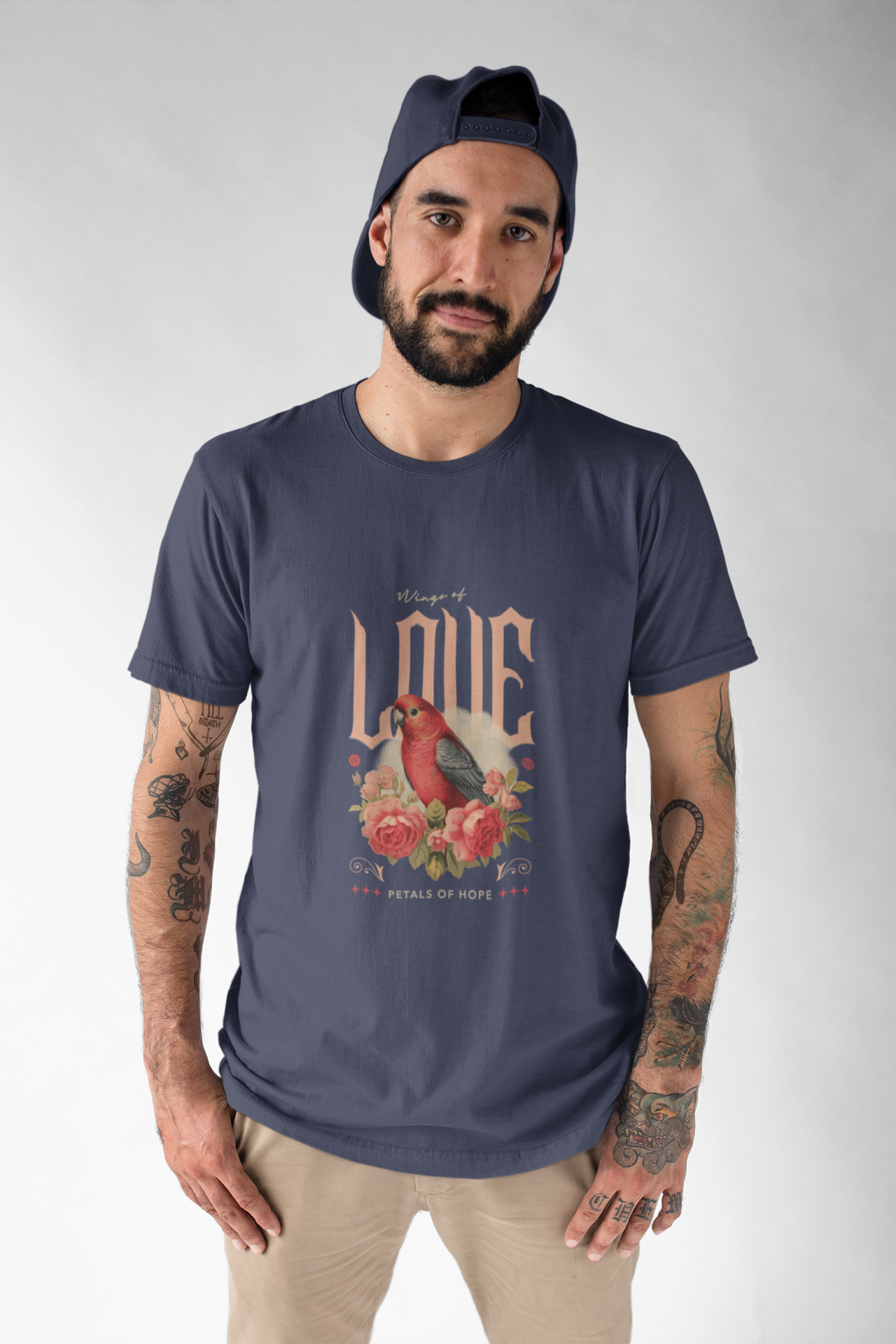 Man wearing a navy t-shirt with a graphic design of two birds and text on a plain background