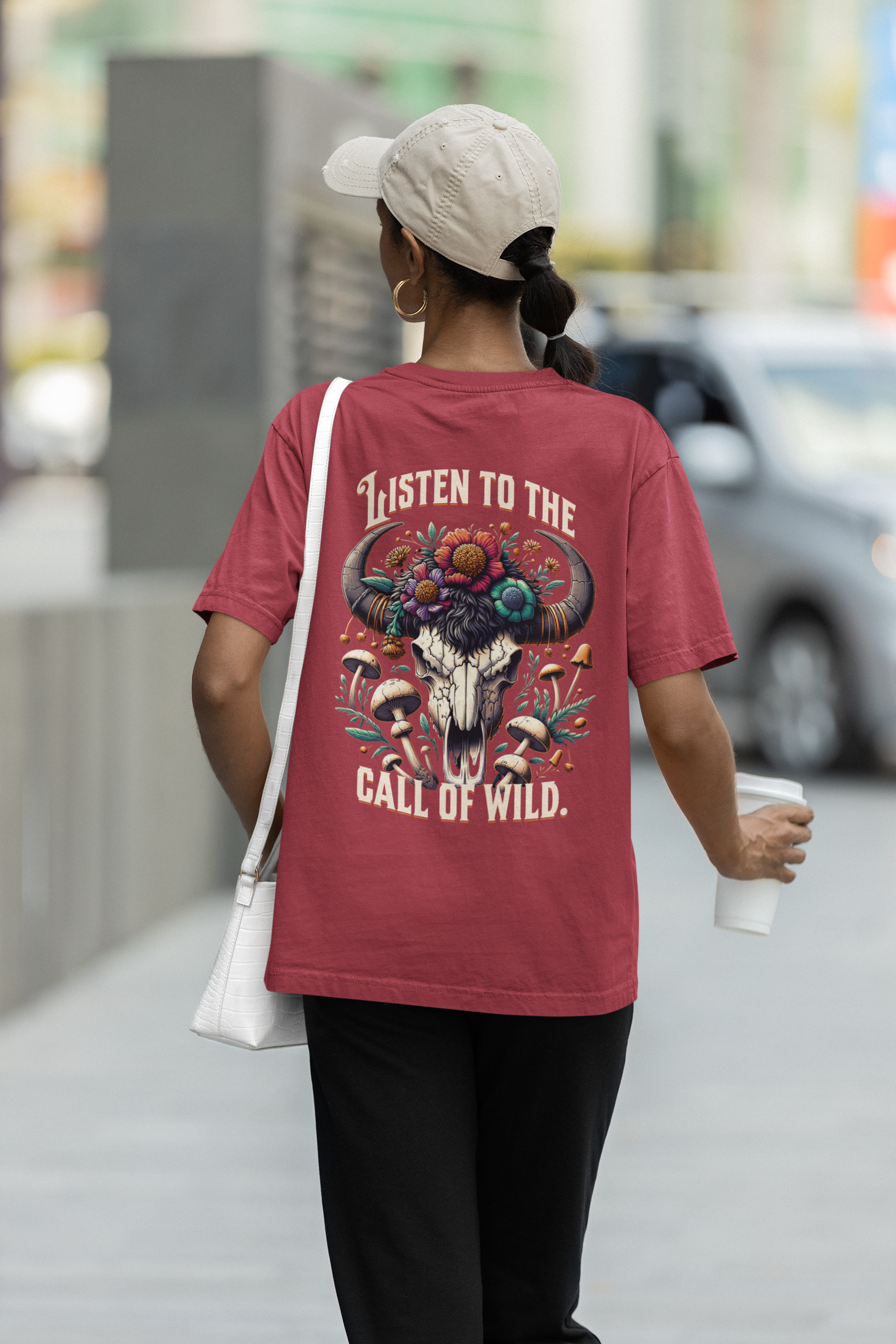 Person wearing a red t-shirt with a graphic design and text, walking outdoors.