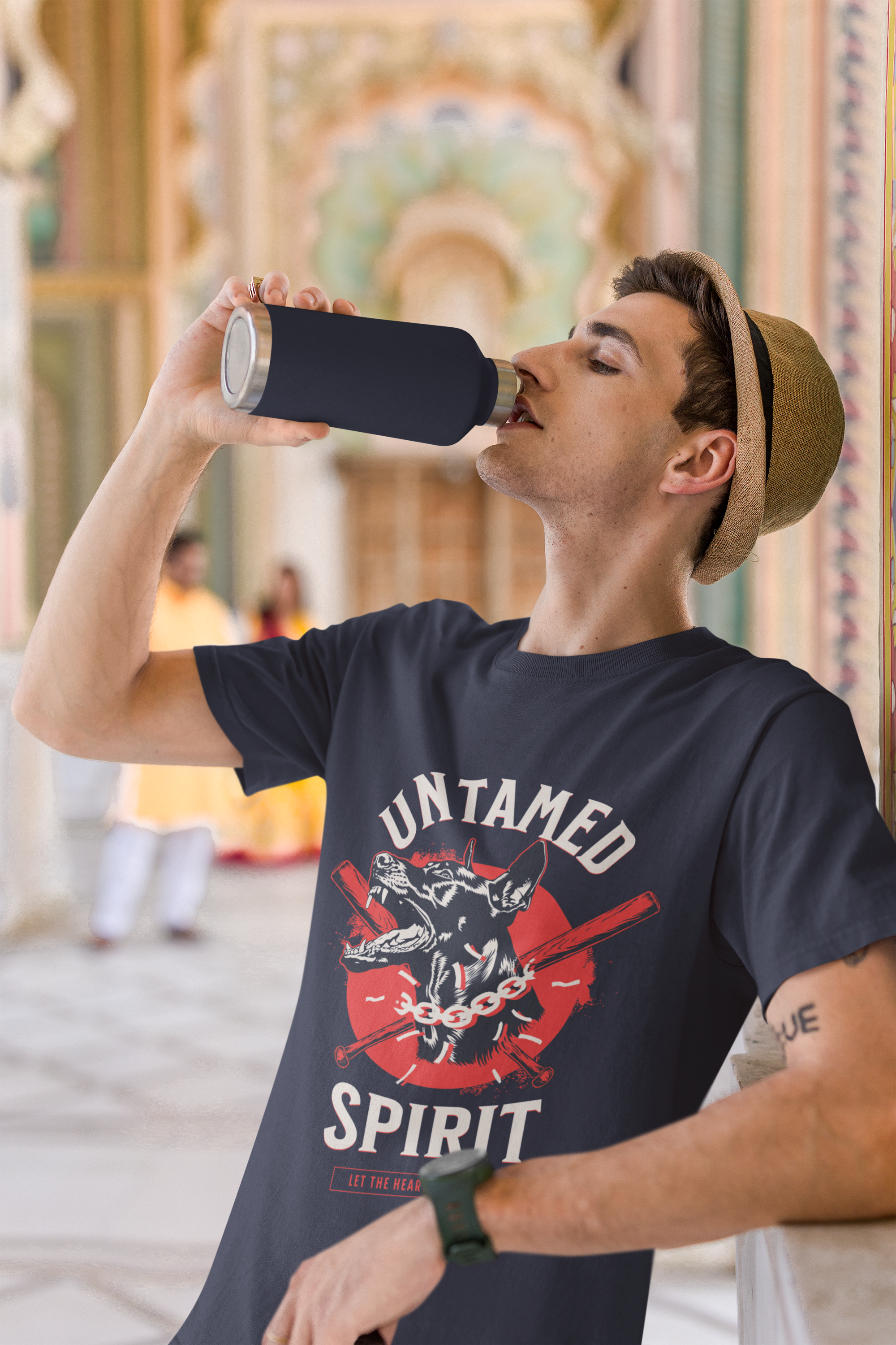 Man drinking from a water bottle wearing a t-shirt with 'Untamed Spirit' design.