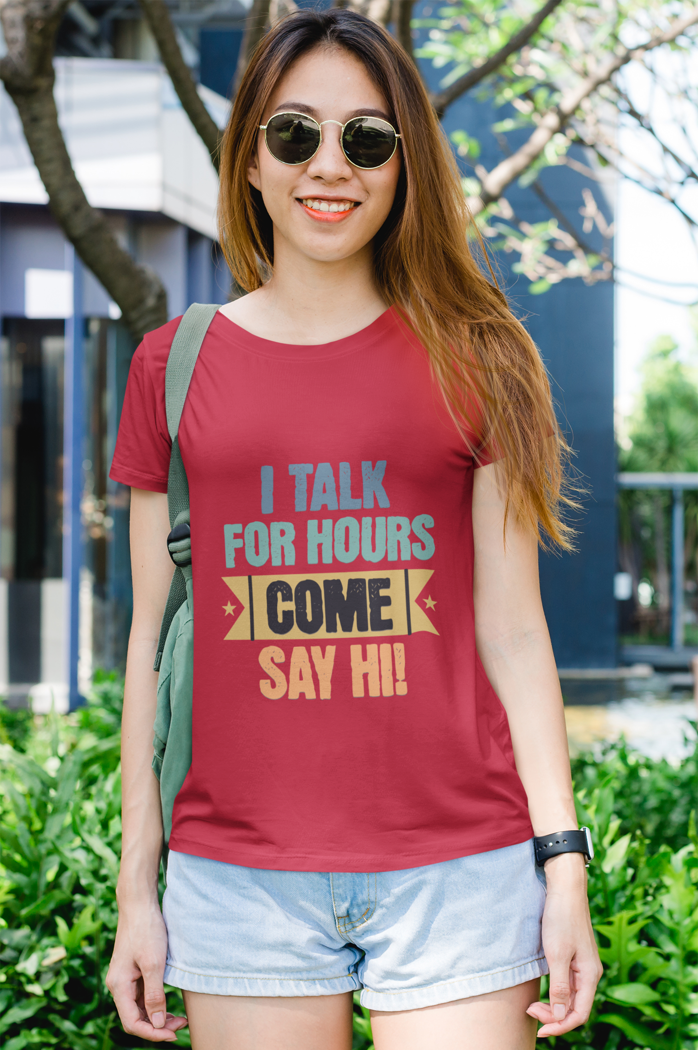 Woman wearing a red t-shirt with a colorful text design outdoors.