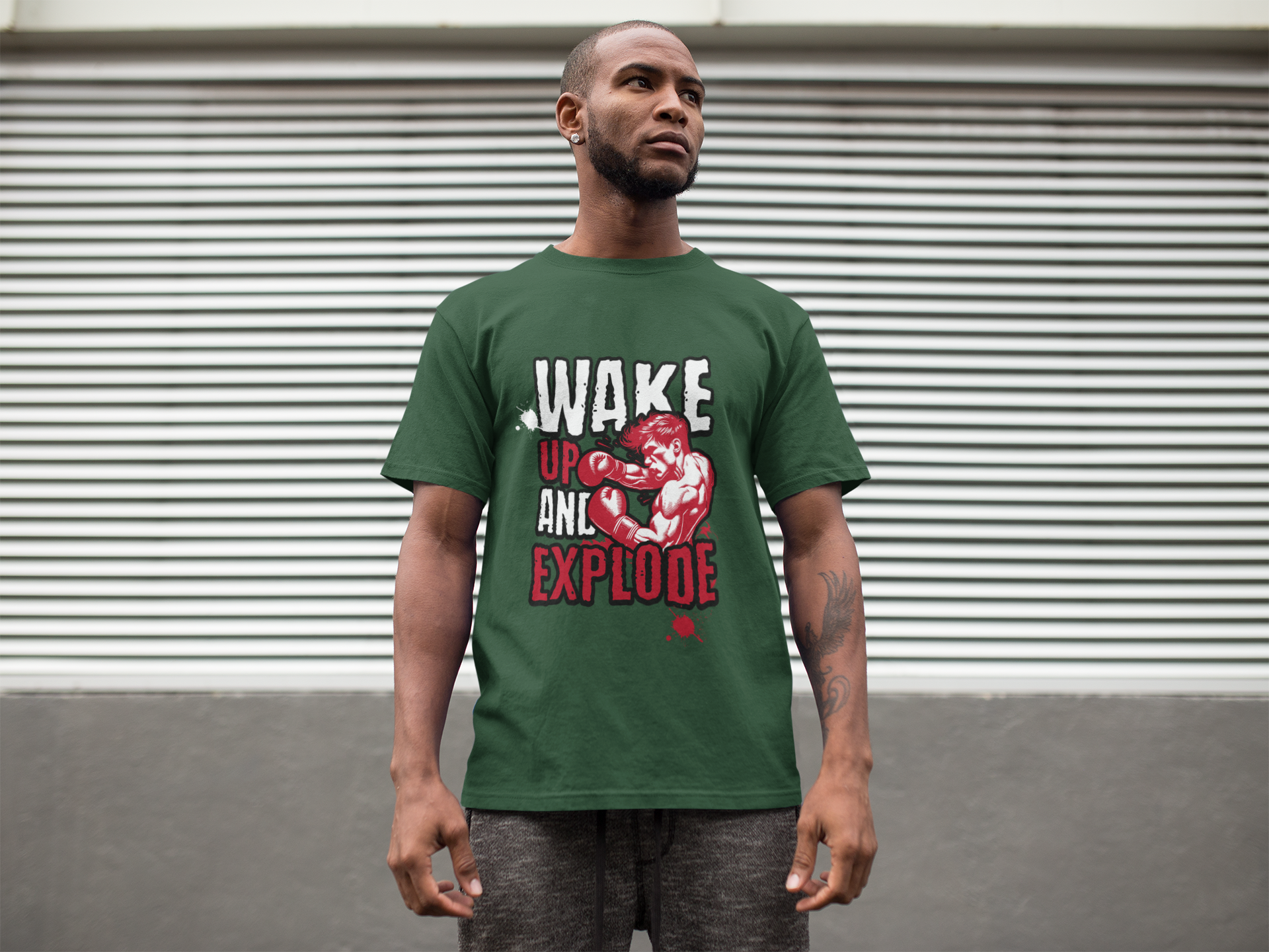 Man wearing a green t-shirt with graphic design and text, standing in front of a closed shutter.